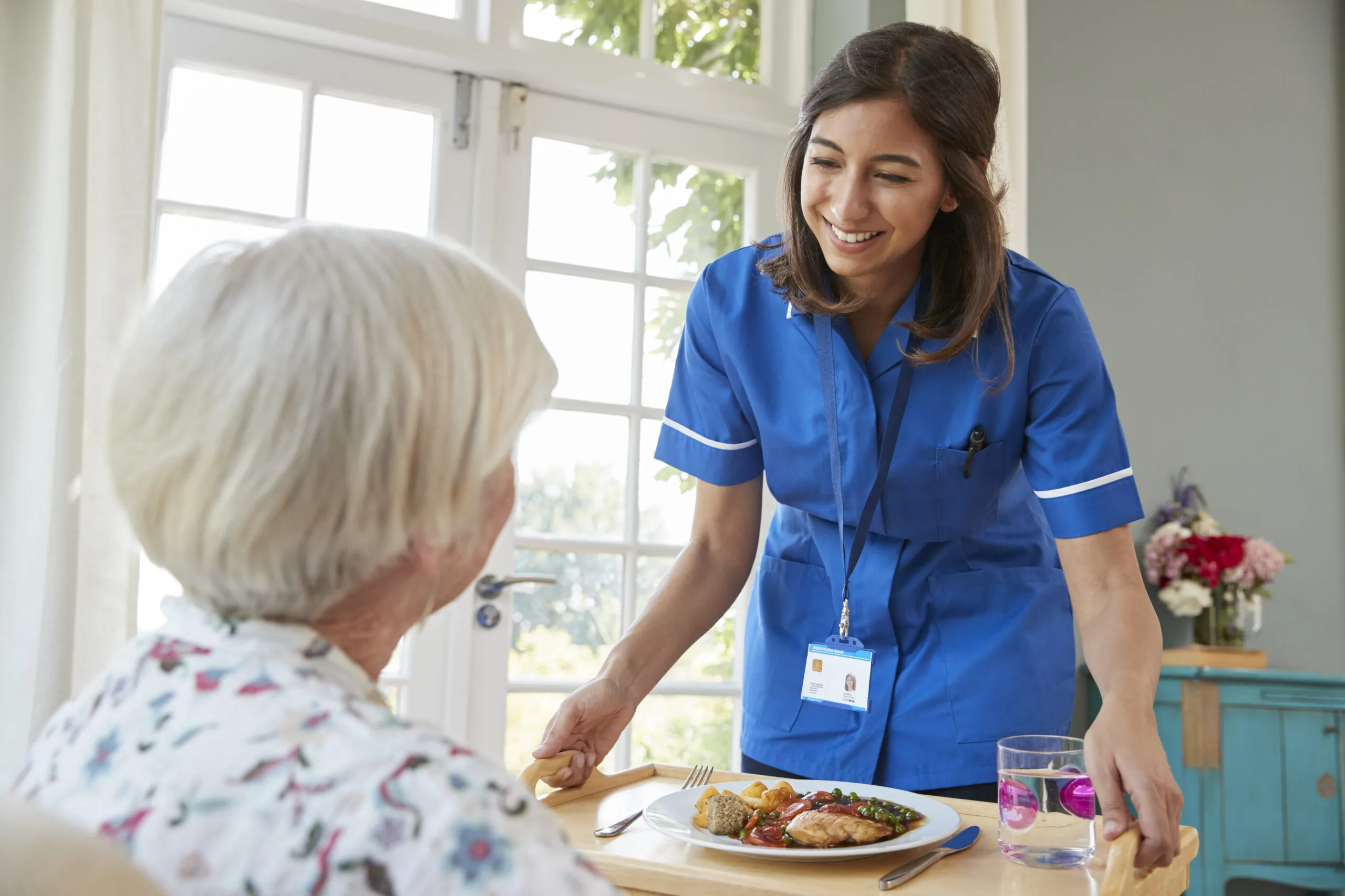Care nurse serving dinner to a senior woman at home senior home care east sacramento CA